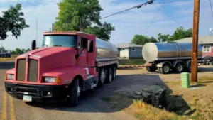 Red Kenworth water tanker truck with trailer parked on a residential street